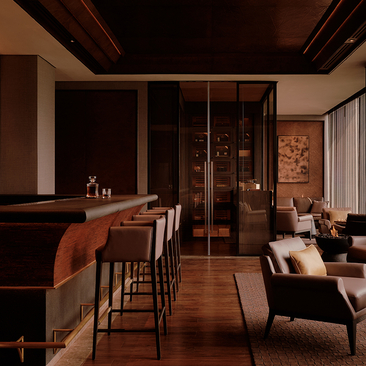 Cigar bar at Aman Nai Lert Bangkok with wooden furnishings, bar seating, and warm ambient lighting.