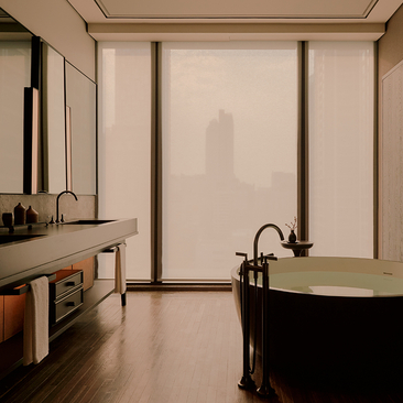 Principal bedroom ensuite at Aman Nai Lert Bangkok, featuring a soaking tub and vanity with minimalist design.