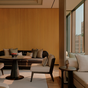 Room 167 at Aman Nai Lert Bangkok with seating area, fluted wood panelling and city views.