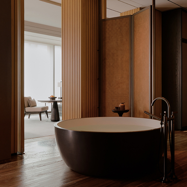 Freestanding black bathtub in a principal bedroom at Aman Nai Lert Bangkok, with wooden architectural details and view to adjoining spaces.
