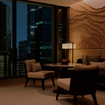 Warm-lit hotel room at Aman Nai Lert Bangkok with mid-century furniture, wavy wood-panelled wall, and city views at night.