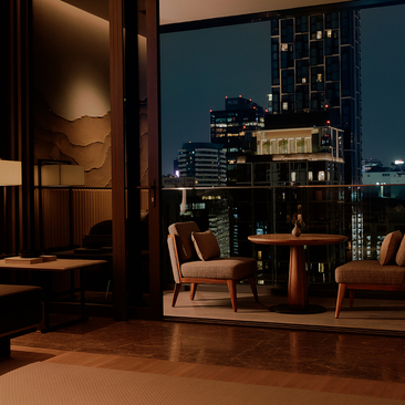 Hotel room at Aman Nai Lert Bangkok with teal accent wall, wooden furniture, and Bangkok skyline views at dusk.