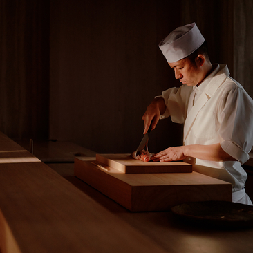 Thai chef preparing ingredients at wooden counter, Aman Nai Lert Bangkok.