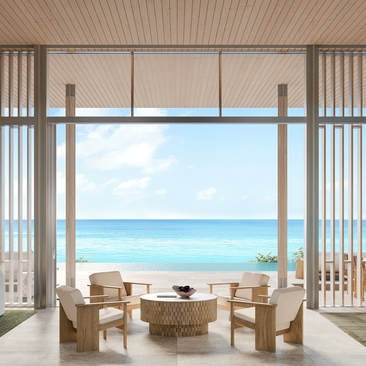 Amanruya villa interior with open-plan living area overlooking turquoise coastal waters through floor-to-ceiling windows.