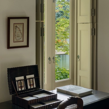 Garden bedroom at Amangalla with desk, open doors and green courtyard views.