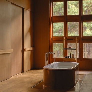 Wooden bathing chamber at Amankora's Paro Lodge with round soaking tub and latticed window.