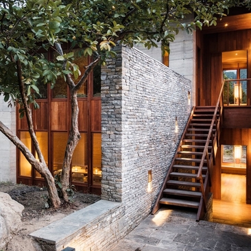 Exterior staircase and entrance to Mo Chhu Suite block at Amankora's Punakha Lodge, with stone walls and warm lighting at dusk.