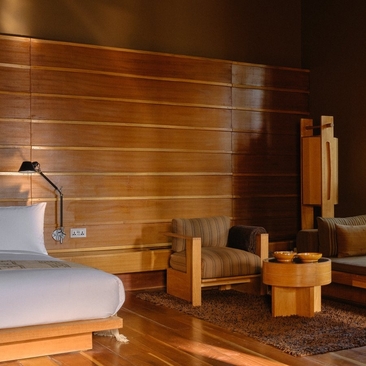 Amankora suite interior in Thimphu with wooden wall panelling, round bed, and carved wooden furniture.