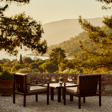 Wine lounge terrace at Amanruya with dining seating overlooking forested hillside at dusk.