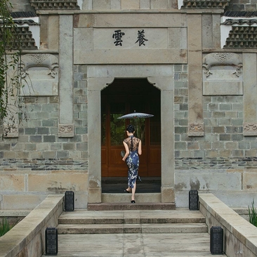 女性穿着汉服在养云安缦度假村的传统建筑门口留影。