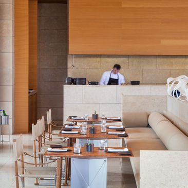 Dining pool restaurant at Amanzoe resort with wooden interiors, set tables, and pool views.