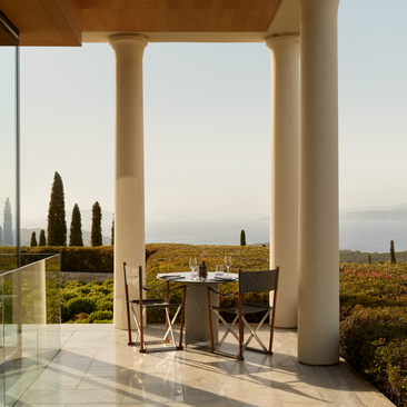 Sala da pranzo principale di Amanzoe con tavolo e sedie sotto un'arcata in pietra con vista sulla campagna greca.
