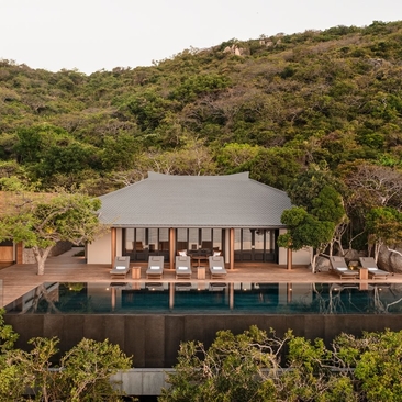 Ocean pool residence at Amanoi in Vietnam, with timber pavilion overlooking water and forested hillside.
