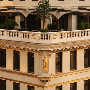 Exterior view of the Crown Building at Aman New York, featuring neoclassical architecture with ornate balconies and arched windows.