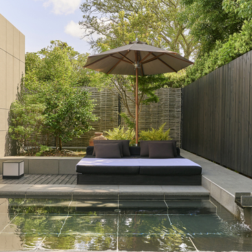 Private onsen at Amanemu with sunshade and seating overlooking calm water.