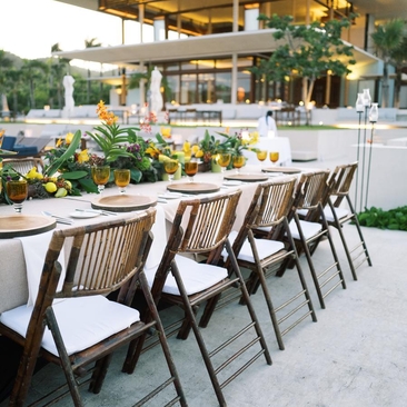 Outdoor dining area at Amanera with wooden chairs arranged along a table, overlooking tropical gardens and the resort beyond.