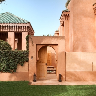 Entrance pavilion at Amanjena resort in Morocco, with terracotta walls and arched doorway framed by green lawn.