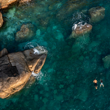 Aerial view of snorkellers exploring clear turquoise waters amongst rocky outcrops at Amanoi, Vietnam.