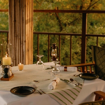 Machan dining experience at Aman-i-Khas with table set amongst treetops and forest views.