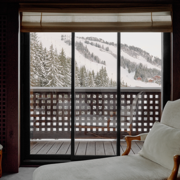 Bedroom window overlooking snow-covered Alpine landscape at Aman Le Mélézin, France.