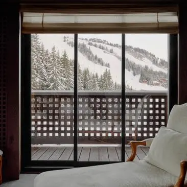 Chambre familiale avec portes-fenêtres donnant sur les montagnes enneigées à Aman Le Mélézin.