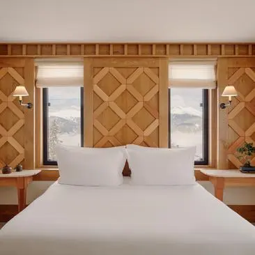 Chambre nord avec lit principal, panneaux muraux géométriques et fenêtres, Aman Le Mélézin.