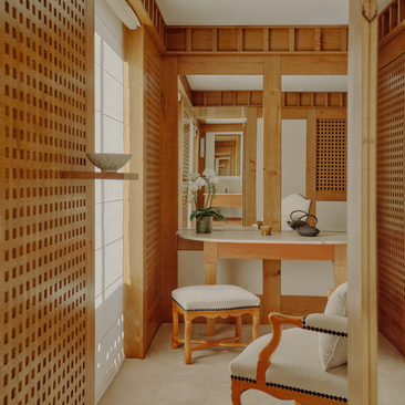 Ski-in accommodation bedroom with wooden furnishings and woven wall panels at Aman Le Mélézin, France.