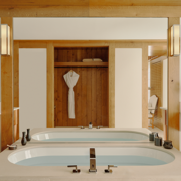 Ensuite bathroom at Aman Le Mélézin with wooden cabinetry and oval soaking tub.