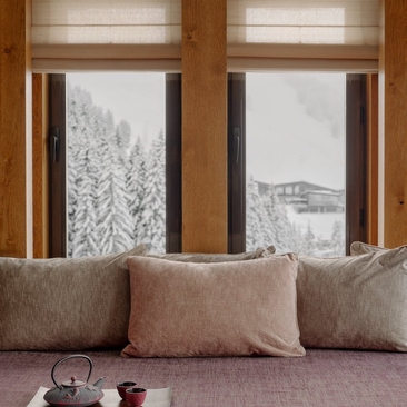 Seating area with cushions overlooking snowy Alpine landscape at Aman Le Mélézin, France.