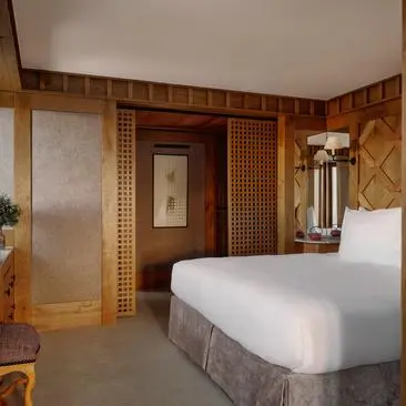 Chambre avec lit double et boiseries en bois clair à Aman Le Mélézin.
