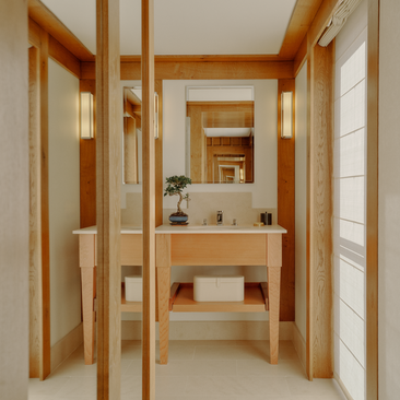 Bathroom at Aman Le Mélézin with wooden cabinetry, open shelving and double vanity sink.