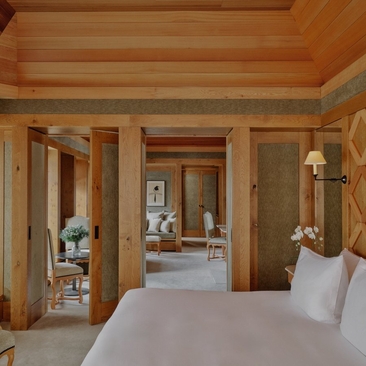 Suite bedroom at Aman Le Mélézin with warm wood interiors and connecting spaces.