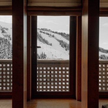Wooden-framed doors at Aman Le Mélézin opening onto snowy Alpine slopes.