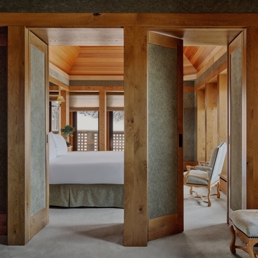 Mélézin suite with open wooden doors revealing a bathroom and bedroom at Aman Le Mélézin.