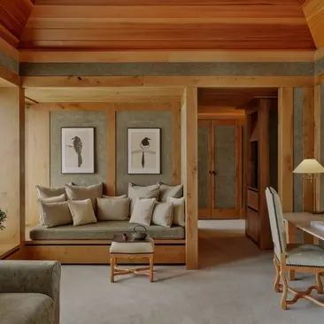 Suite bedroom with wooden window seat and cushions at Aman Le Mélézin resort.