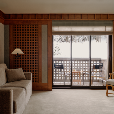 Accommodation suite at Aman Le Mélézin with views over the ski piste from a glazed balcony door.