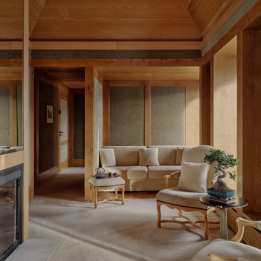 Accommodation suite at Aman Le Mélézin with wooden interiors, seating area and glass doors opening to terrace.