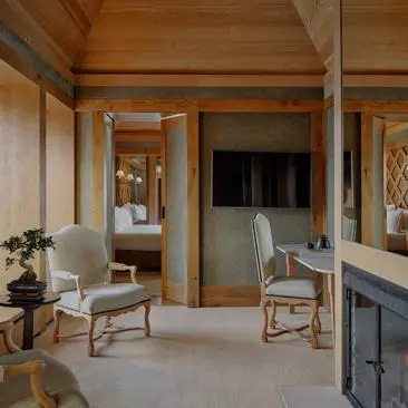 Suite Vanoise bedroom at Aman Le Mélézin resort, with wooden beams and neutral tones.
