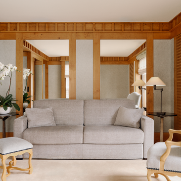Accommodation suite at Aman Le Mélézin with grey sofa and wooden architectural frames.