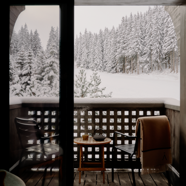 Suite at Aman Le Mélézin with views of snow-covered Alpine forest through large windows.
