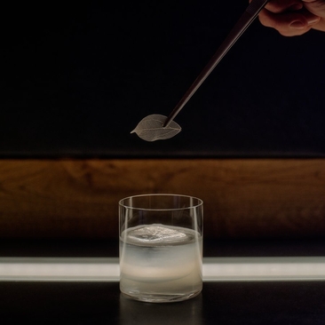 Cocktail being prepared at Aman Le Mélézin with a bar spoon stirring a clear drink in a glass.