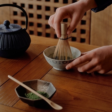 Hands whisking matcha tea with bamboo whisk at Aman Le Mélézin, France.