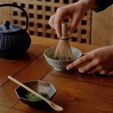 Cérémonie du thé japonaise à Aman Le Mélézin, les mains préparant le matcha avec un fouet en bambou.