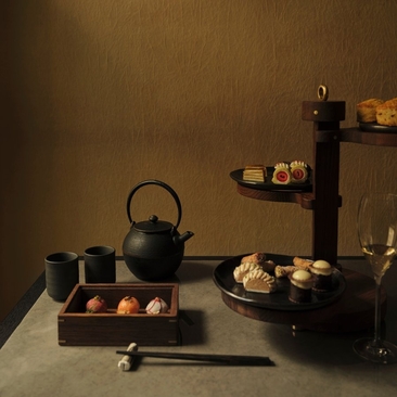 Afternoon tea service at Aman New York with teapot, cups, and pastries on dark table
