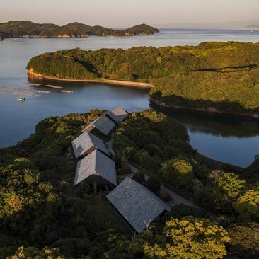 Amanemu's exterior overlooking moss-covered lava fields and still waters in Ise Shima, Japan.