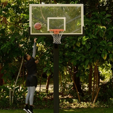 Jugador de baloncesto en la cancha al aire libre de Amanera, rodeado de vegetación tropical.