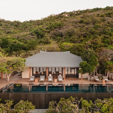 Ocean pool residence at Amanoi, Vietnam, surrounded by verdant hillside and water.