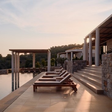 安缦卓熠度假村的三卧室别墅露台，配有躺椅，俯瞰平静水景。