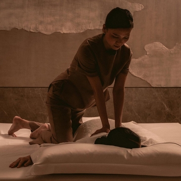 Therapist performing a massage treatment on a guest at Aman Nai Lert Bangkok spa.