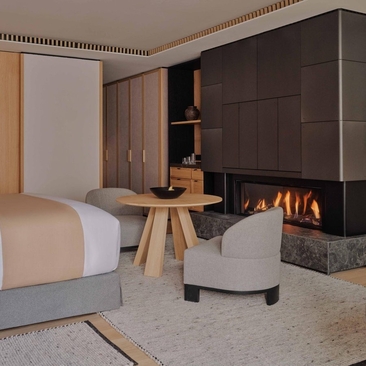 Junior Suite at Aman Rosa Alpina with bed, fireplace and seating area.